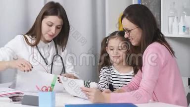 一个女人带着一个年轻的女儿在办公室和一位儿科<strong>医生</strong>交谈。
